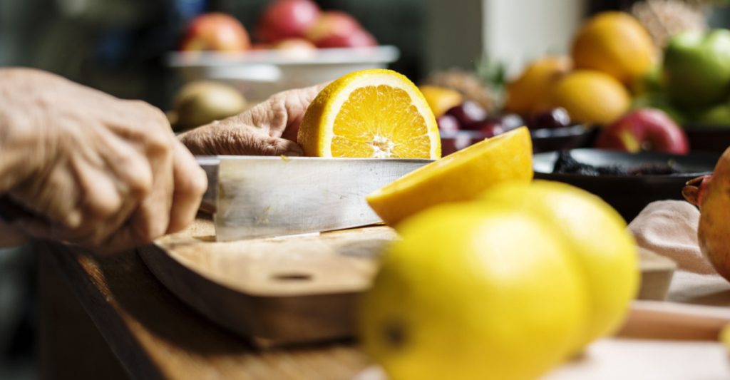 Close up of a hand cutting an orange