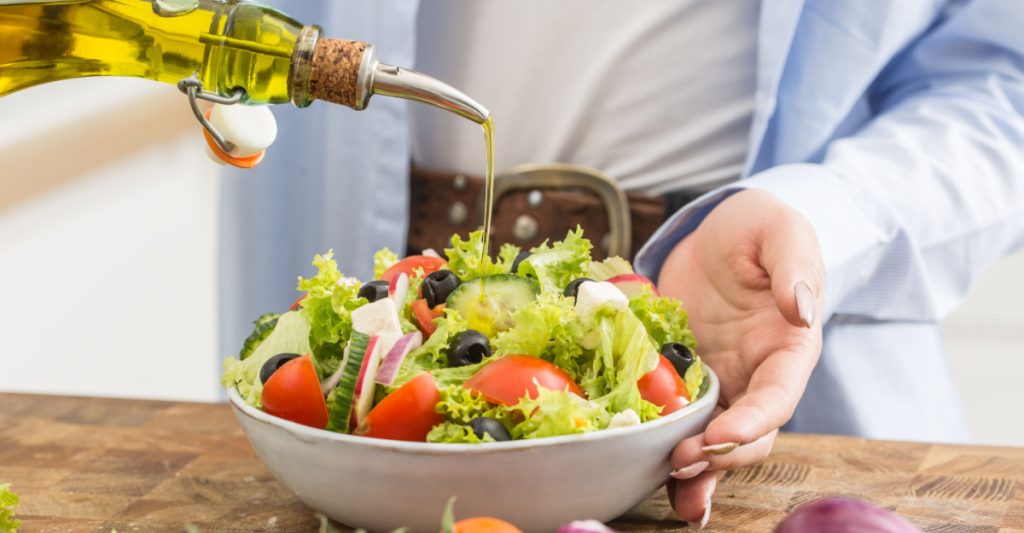 Woman pouring oil on a salad