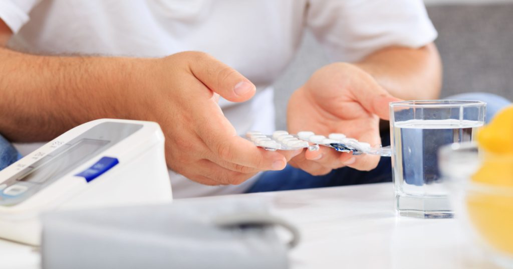 Man taking medication after measuring his blood pressure