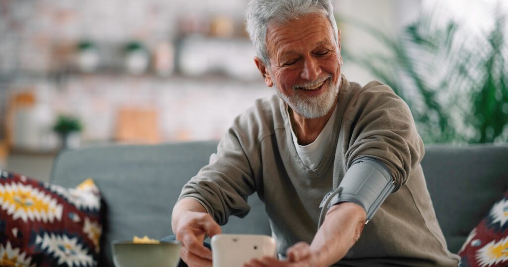 Smiling man measuring his blood pressure