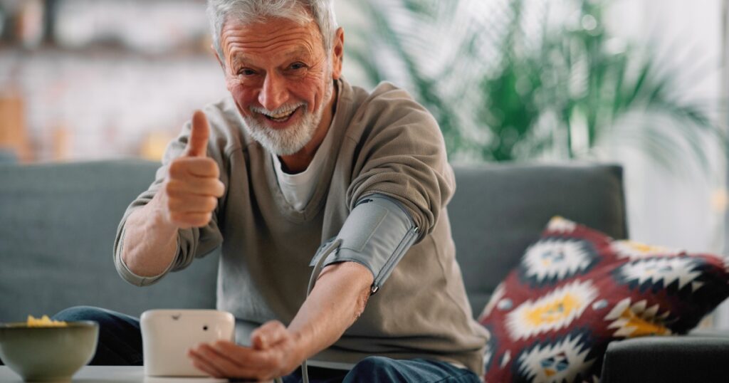 Man measuring his blood pressure and showing a thumbs up