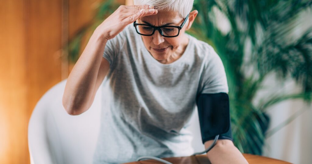 Close up of a woman measuring her blood pressure and looking worried