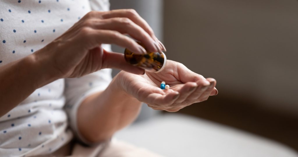 A close up of woman with pills in her hand